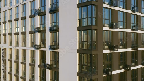 Aerial side view of a newly built modern high-rise apartment building facade. Close-up elevator shot at sunset photo