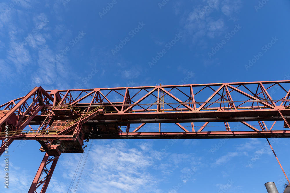 Overhead trusses, catwalks, and stairs of a massive industrial structure against a deep blue sky, horizontal aspect Overhead trusses, catwalks, and stairs of a massive industrial structure against a deep blue sky, horizontal aspect