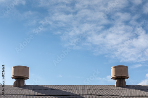 Giant air turbines on the roof of an industrial warehouse building, blue sky with clouds creative copy space, horizontal aspect photo