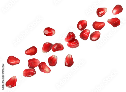 Ripe juicy pomegranate seeds falling on white background