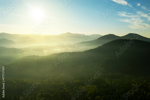 Sun shining over forest in misty mountains. Drone photography