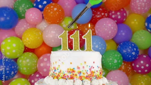 Cake with burning candles number 111. A tasty Birthday Cake on a bright festive background of colorful balloons. photo