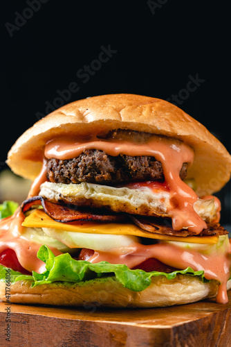 Fresh grilled homemade burgers with beef, tomato, fried egg, cheese and lettuce on rustic wooden background. fast food and junk food concept. fresh tasty burger on dark background.
