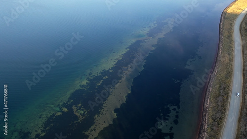 Aerial view with a top view of the clear sea and the road