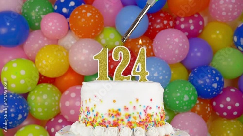 Cake with burning candles number 124. A tasty Birthday Cake on a bright festive background of colorful balloons. photo