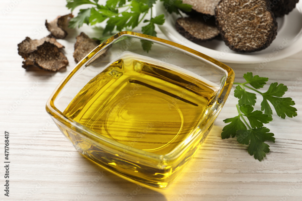 Fresh truffle oil in glass bowl and parsley on white wooden table, closeup Fresh truffle oil in glass bowl and parsley on white wooden table, closeup