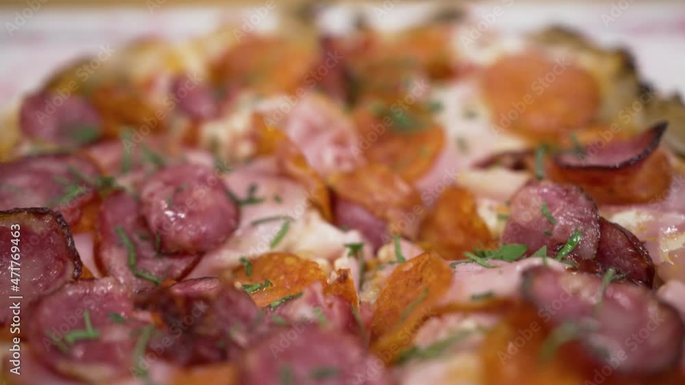 Meat pizza cut into pieces close-up, salami slices sprinkled with fresh dill Meat pizza cut into pieces close-up, salami slices sprinkled with fresh dill