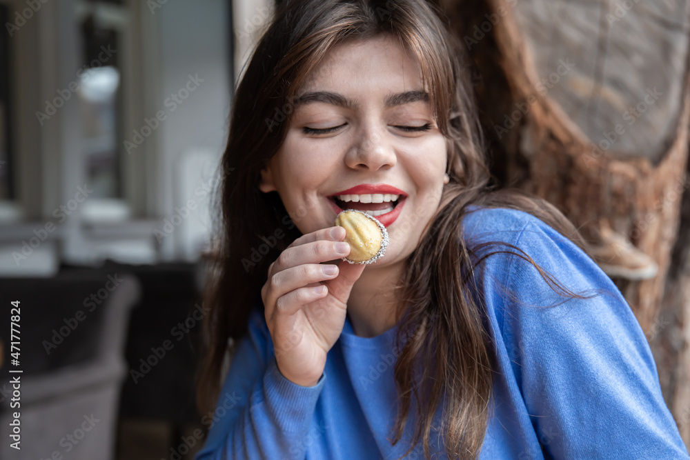 A young woman eating walnut-shaped shortbread sandwich cookies. A young woman eating walnut-shaped shortbread sandwich cookies.