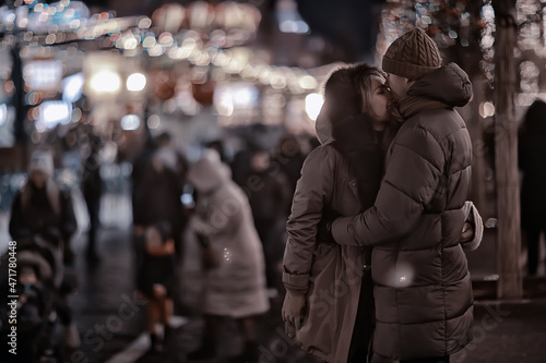 couple in love on a christmas walk in the city, evening snowfall december holiday new year