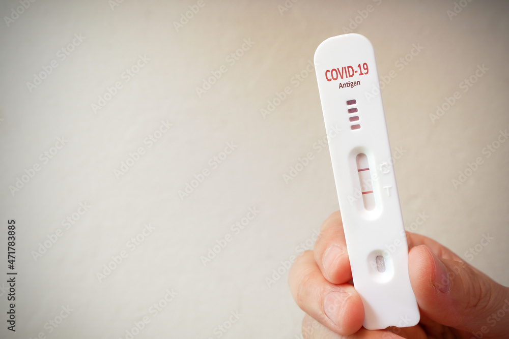 Hand holding antigen test kit strip or ATK with positive result of covid-19 infected , self rapid testing concept with copy space Hand holding antigen test kit strip or ATK with positive result of covid-19 infected , self rapid testing concept with copy space