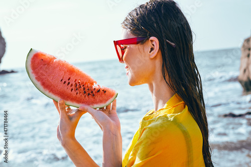 cheerful woman near the ocean with watermelon posing