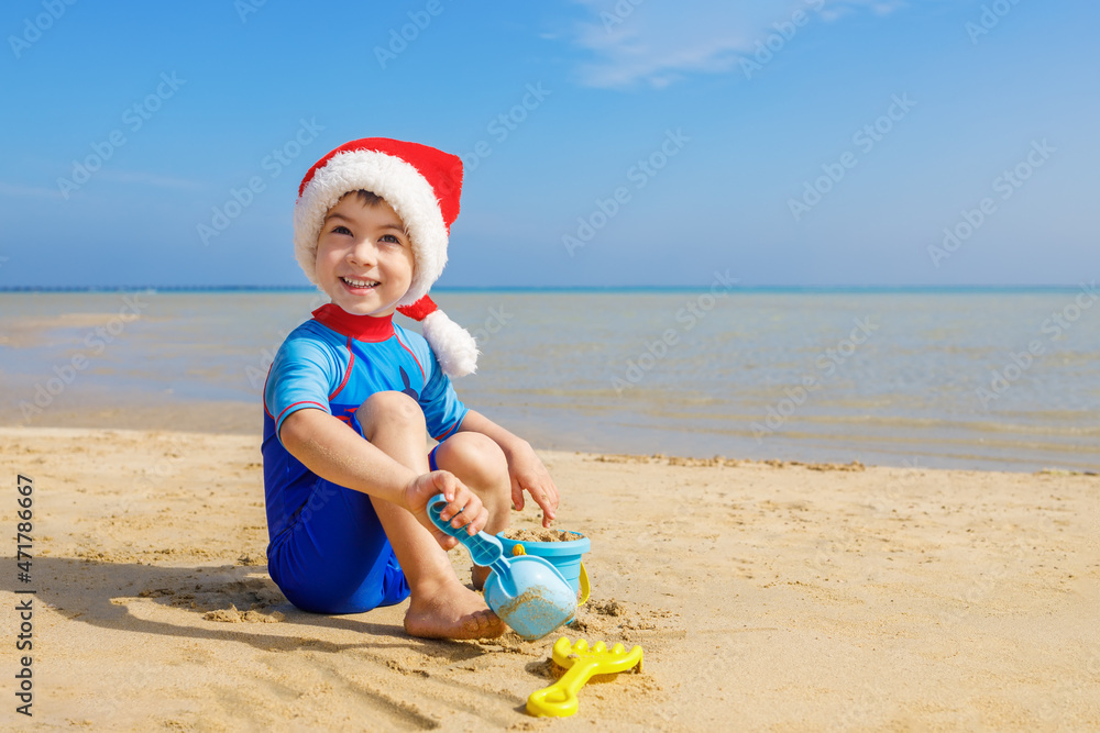 smiling child boy in santa hat playing with toys for sand smiling child boy in santa hat playing with toys for sand
