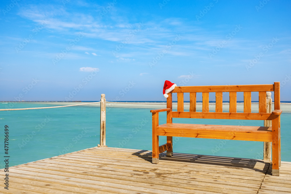 Santa hat on wooden bench on the pontoon overlooking the turquoise sea