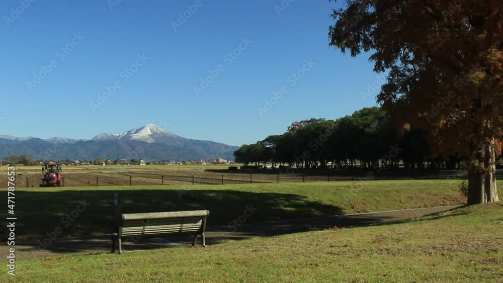 雪化粧した伊吹山と農地を耕すトラクターが見える風景