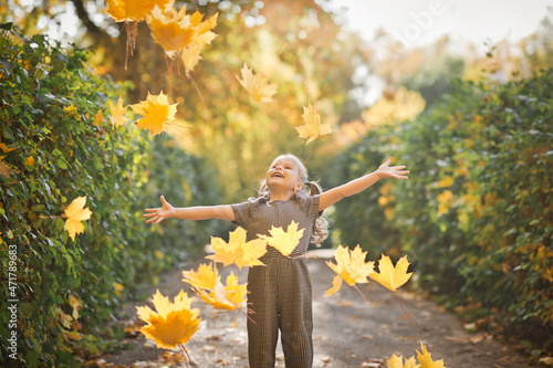 A little daughter is playing with autumn leaves in the park 3382.