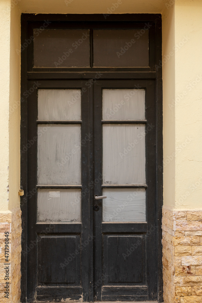 Obraz premium Closed old wooden door with glass in building, vertical format and no person