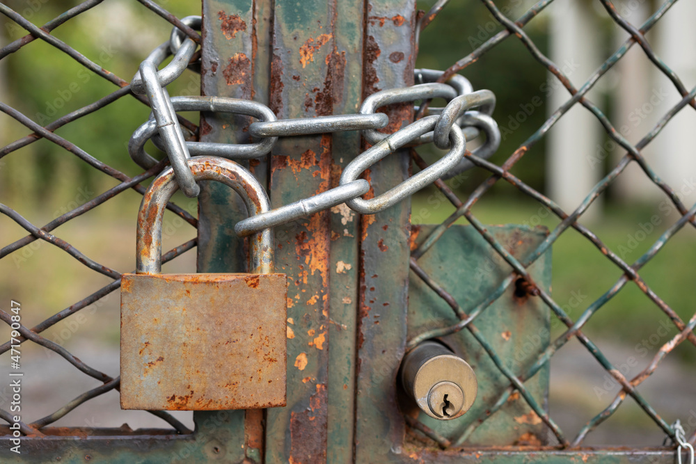 Lock down, old rusty padlock on a mesh fence with metal chain, safety first, no person 