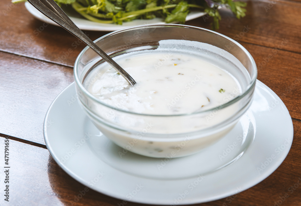 yogurt soup with herbs in a plate on a wooden table.spas yogurt soup with herbs in a plate on a wooden table.spas