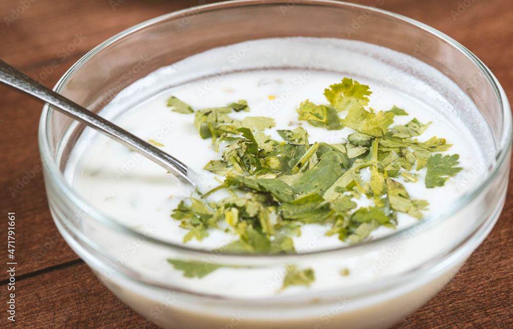 yogurt soup with herbs in a plate on a wooden table.spas yogurt soup with herbs in a plate on a wooden table.spas