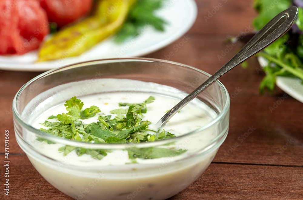 yogurt soup with herbs in a plate on a wooden table.spas yogurt soup with herbs in a plate on a wooden table.spas