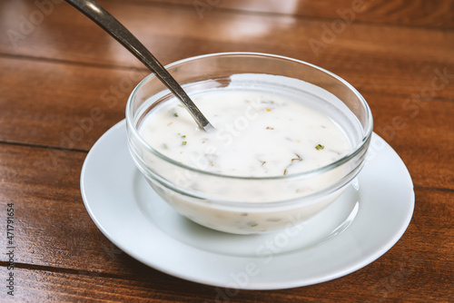 yogurt soup with herbs in a plate on a wooden table.spas