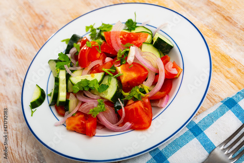 Healthy vegetable salad of sliced fresh tomatoes, cucumber, red onion and greens with olive oil