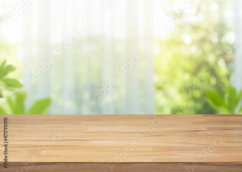 Selective focus.Empty of wood table top on blur of curtain with window view green from garden