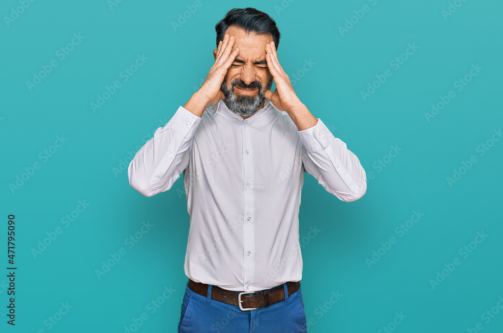 Middle aged man with beard wearing casual white shirt suffering from headache desperate and stressed because pain and migraine. hands on head. Middle aged man with beard wearing casual white shirt suffering from headache desperate and stressed because pain and migraine. hands on head.