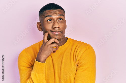 Obraz na plátně Young black man wearing casual yellow sweater thinking concentrated about doubt