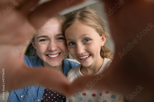 Close up head shot happy millennial mother and small adorable sincere child daughter showing heart symbol with fingers, candid two generations family demonstrating loving feelings, relations concept.