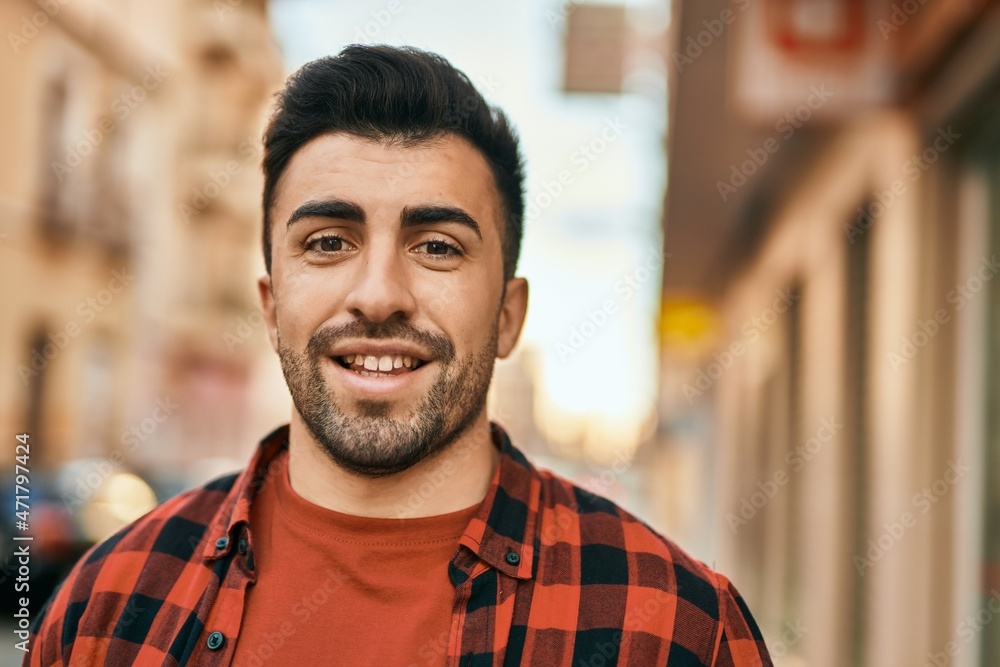 Obraz premium Young hispanic man smiling happy standing at the city.