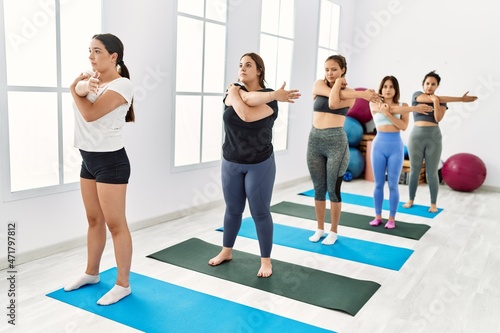 Group of young hispanic women concentrated stretching at sport center.