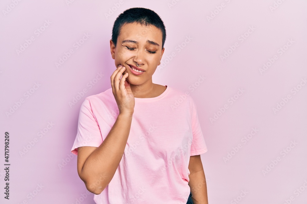 Beautiful hispanic woman with short hair wearing casual pink t shirt touching mouth with hand with painful expression because of toothache or dental illness on teeth. dentist Beautiful hispanic woman with short hair wearing casual pink t shirt touching mouth with hand with painful expression because of toothache or dental illness on teeth. dentist