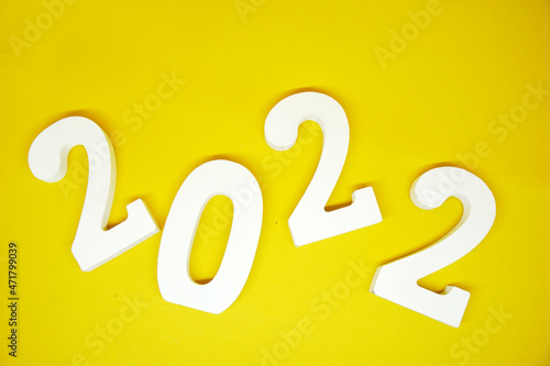 Flat lay Happy New year 2022 , 2022 number wood object on yellow background and copy space - yellow color new year celebrate and business resource concept - marketing resource design template 