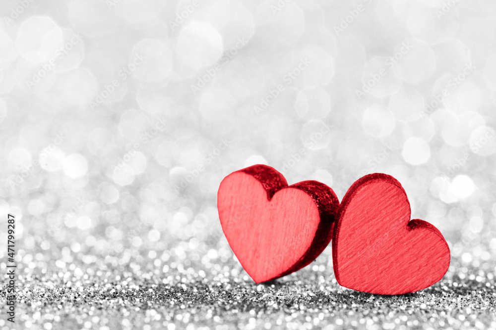 Two red hearts on glittering background