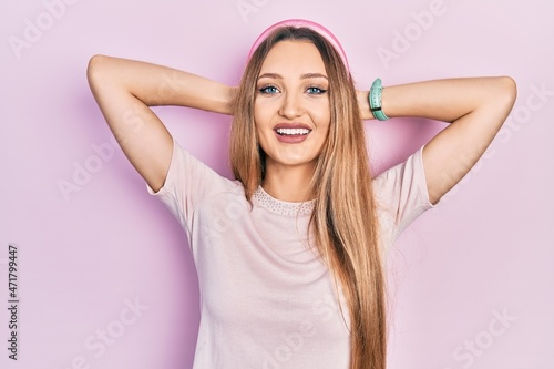 Young blonde girl wearing casual clothes relaxing and stretching, arms and hands behind head and neck smiling happy