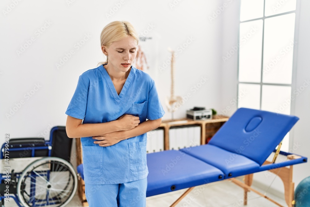Beautiful caucasian physiotherapist woman working at pain recovery clinic with hand on stomach because nausea, painful disease feeling unwell. ache concept.