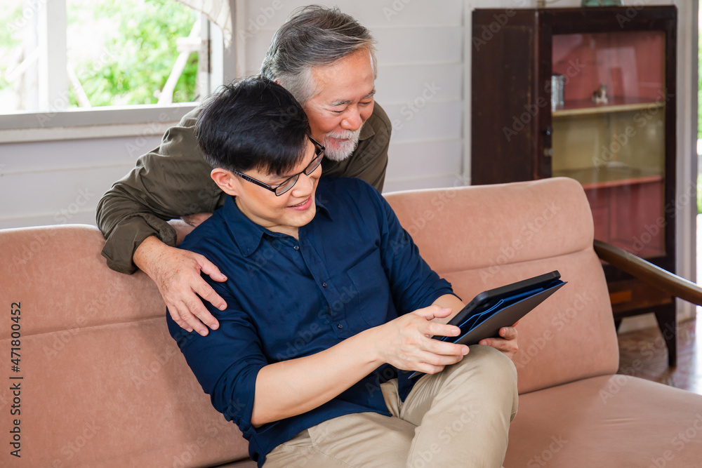 Adult son and senior asian father using tablet smartphone in living room, Happy family concepts