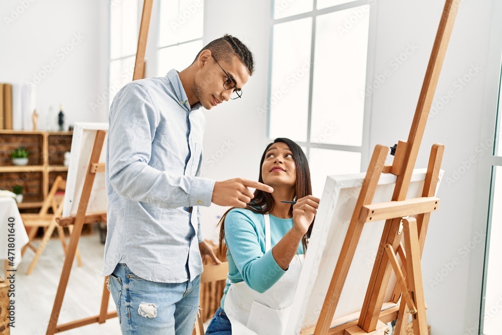 Obraz premium Young latin painter couple with serious expression painting at art studio