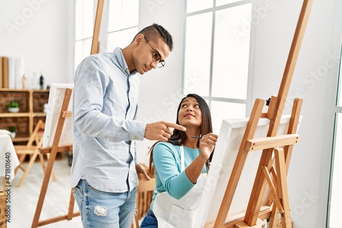 Young latin painter couple with serious expression painting at art studio