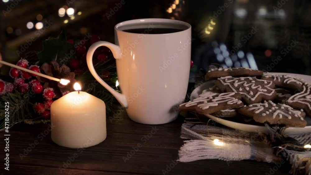 Lighting a candle. Cozy still life with a mug of hot drink and traditional Christmas gingerbread cookies Lighting a candle. Cozy still life with a mug of hot drink and traditional Christmas gingerbread cookies
