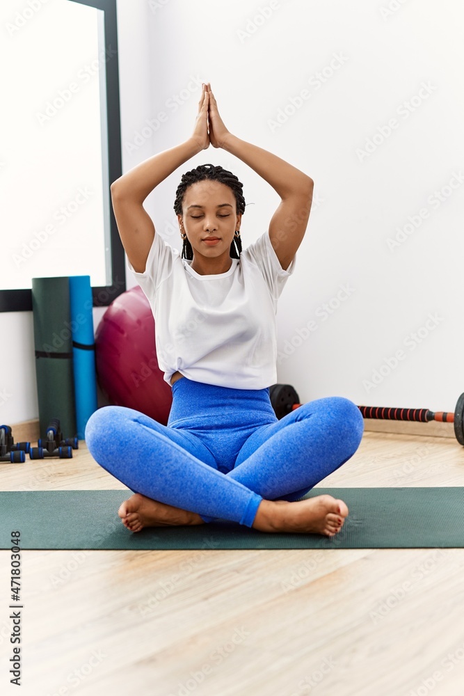 Young african american woman training yoga at sport center