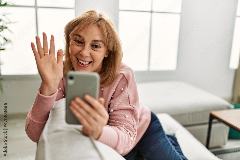 Middle age blonde woman making video call using smartphone at home. Middle age blonde woman making video call using smartphone at home.