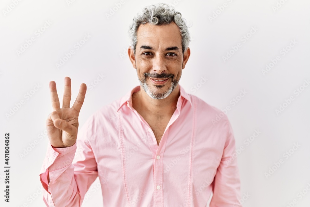 Middle age hispanic man standing over isolated background showing and pointing up with fingers number three while smiling confident and happy. Middle age hispanic man standing over isolated background showing and pointing up with fingers number three while smiling confident and happy.