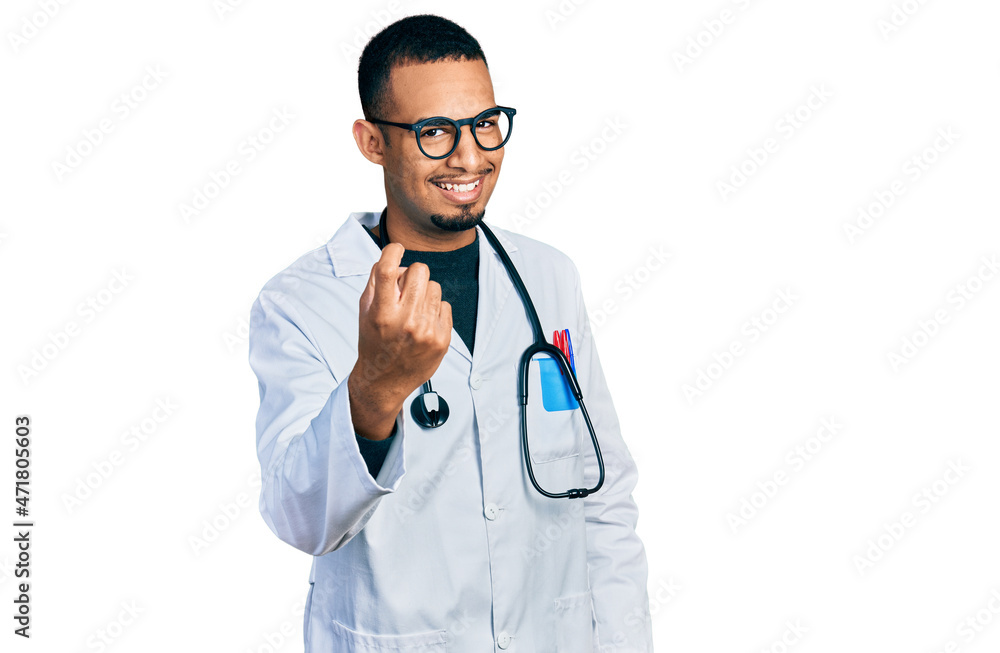 Young african american man wearing doctor uniform and stethoscope beckoning come here gesture with hand inviting welcoming happy and smiling