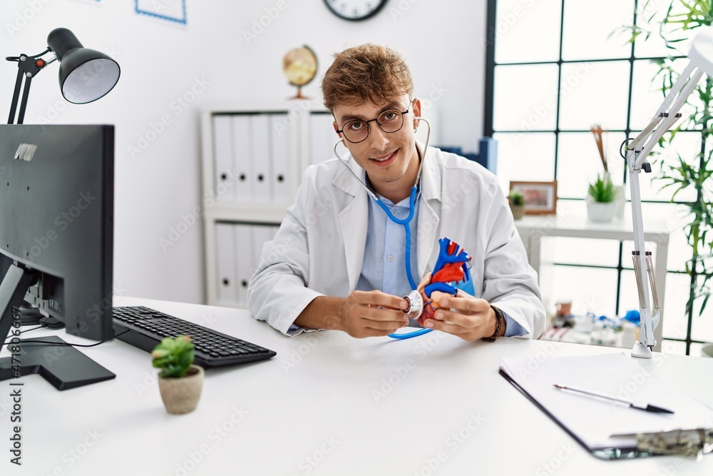 Young caucasian man wearing doctor uniform auscultating heart at clinic Young caucasian man wearing doctor uniform auscultating heart at clinic