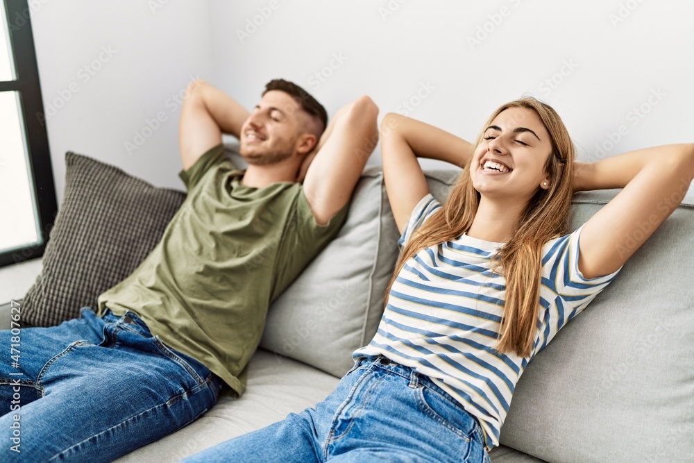 Young hispanic couple smiling happy relaxed with hands on head sitting on the sofa at home. Young hispanic couple smiling happy relaxed with hands on head sitting on the sofa at home.