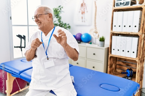 Senior physiotherapy man working at pain recovery clinic disgusted expression  displeased and fearful doing disgust face because aversion reaction. with hands raised