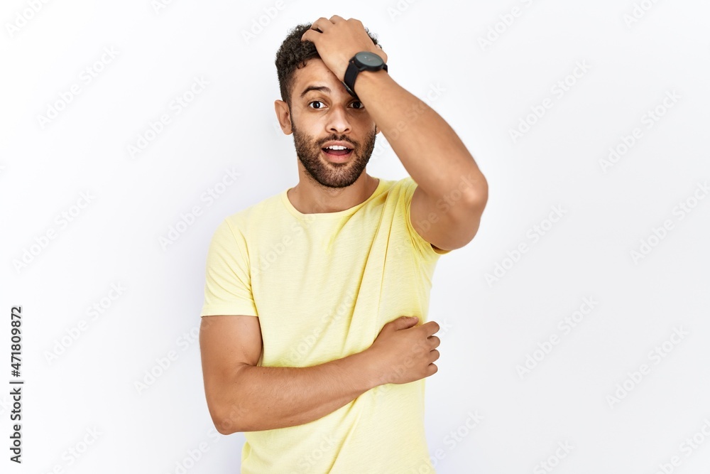 Fototapeta premium Arab young man standing over isolated background surprised with hand on head for mistake, remember error. forgot, bad memory concept.