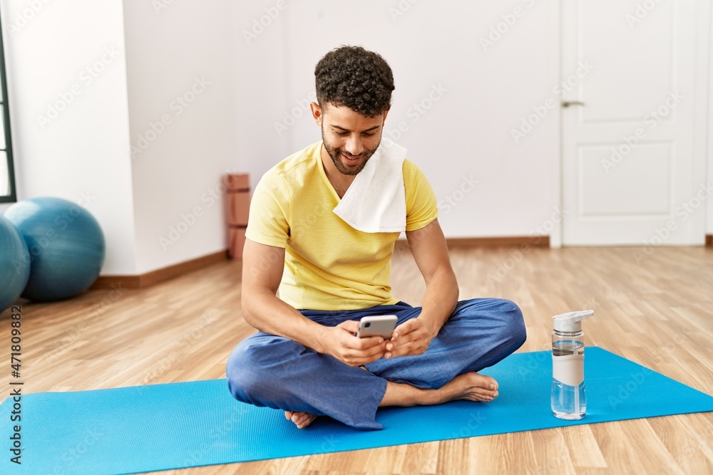 Young arab sporty man smiling happy using smartphone at sport center.